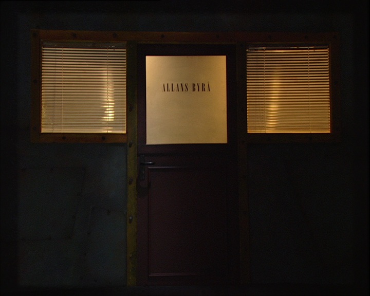 Camera flying down a dark ventilation duct toward a lit sign reading Allans Byrå